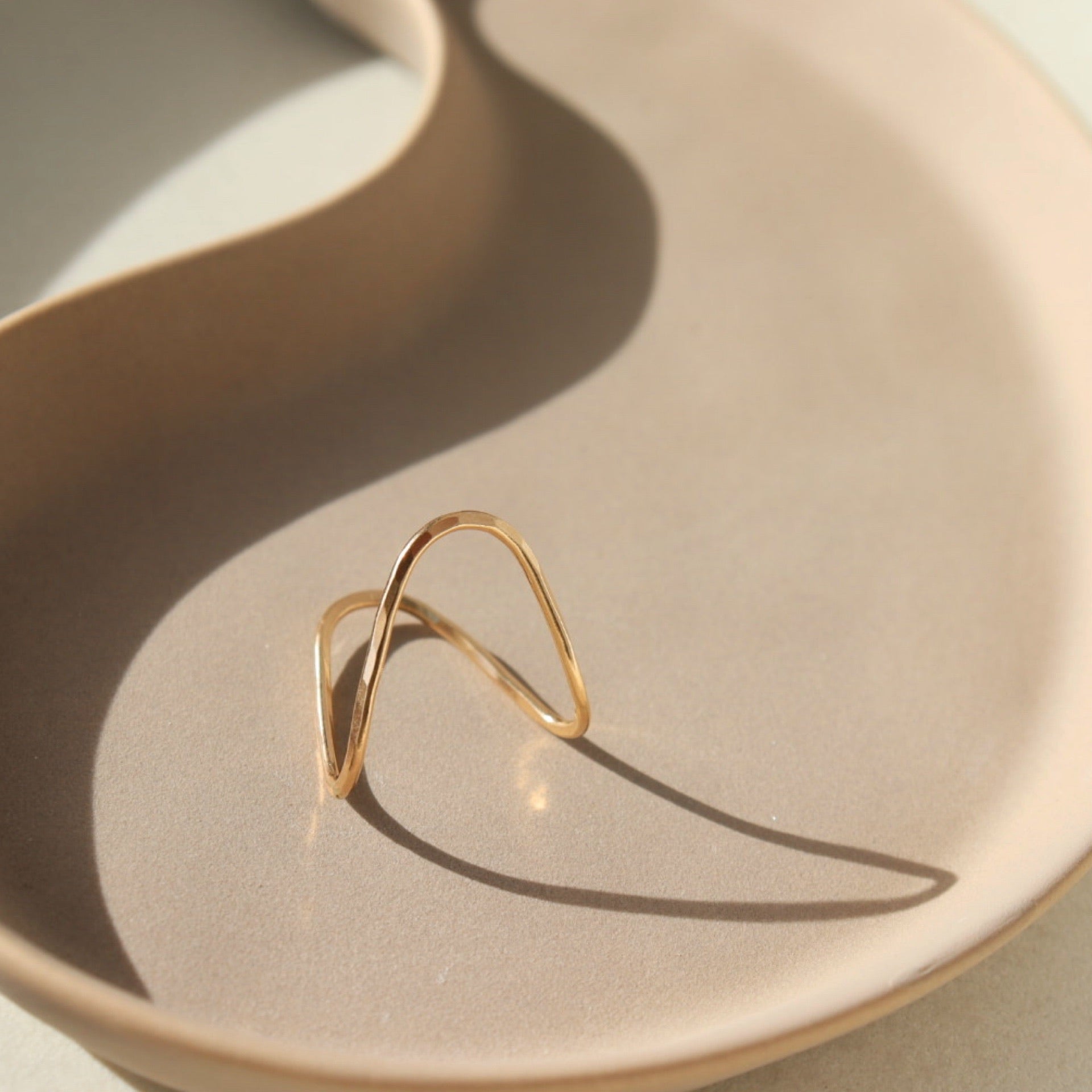 14k gold fill Rising tide Ring on a peach plate in the sunlight.