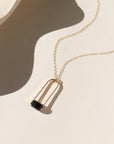 Sable Pendant featuring a smooth blue tiger’s eye gemstone framed by a gold arch