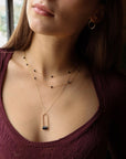 Sable Pendant featuring a smooth blue tiger’s eye gemstone framed by a gold arch