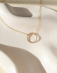 14k gold fill spiral circle pendant on a dainty chain displayed on a white plate