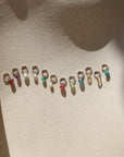 group of tiny birthstones on jump rings in the sun on a light dish