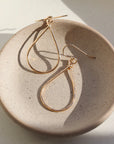 14k gold fill earring, these earring a a teardrop shape with a hook for the earring to enter your ear. The Essential hoops are place on a gray plate, in the sunlight. Earrings are hypoallergenic, nickel free. Handmade in Eau Claire, Wisconsin.