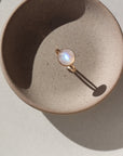 14k gold fill moonrise ring laid on a gray plate in the sunlight. This ring features a simple gold band with hammering and a moonstone