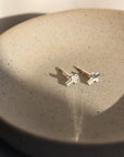 925 Sterling Silver cross stud earrings. Sitting on a gray plate sitting in the sunlight.