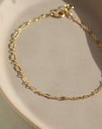 14k gold fill Sylvie bracelet laid on a tan plate in the sunlight.