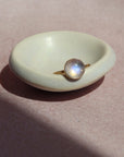 14k gold fill Moonrise Ring placed on a white dish in the sun. - Token Jewelry