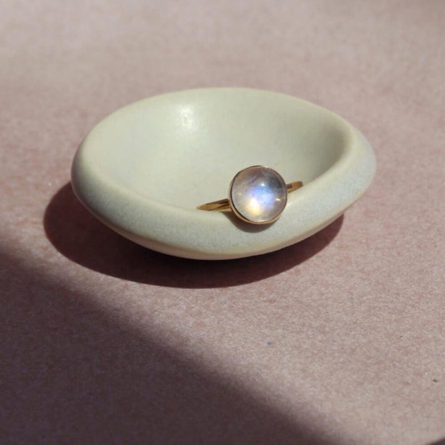 14k gold fill Moonrise Ring placed on a white dish in the sun. - Token Jewelry