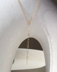 14k solid gold necklace laid across white pot. Handmade in Eau Claire Wisconsin.
