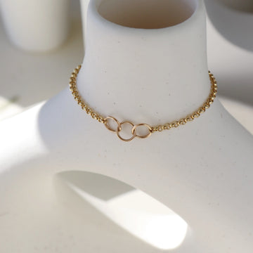 14k gold fill friendship bracelet placed on a white pot. this pot is placed in the sunlight. This bracelet features circle links representing a relationship. Perfect for you and your friend and or someone you are in a relationship with. these circle links are then connected by the Dylan chain.