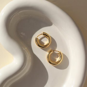 14k gold fill everyday hoops placed on a white plate sitting in the sunlight. These earring are the perfect everyday earring made to live in.