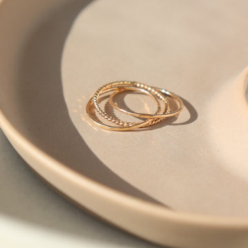 14k gold fill Tribeca Ring laid on a tan plate in the sunlight. This ring features a super cute laid look but its one ring. 