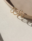 14k gold fill wishbone studs laid on a tan plate in the sunlight.