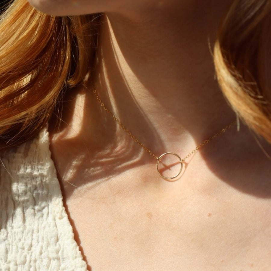 Model is wearing the 14k gold fill Eternity Necklace. This necklace features an open circle disc that is attached to our simple chain. Token Jewelry is hypoallergenic and nickel free. - Token Jewelry