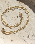 14k gold fill piper bracelet set on a tan stone plate in the sunlight.