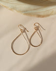 essential hoops 14k gold filled have two different earring sizes. These earrings are placed on a peach colored paper and are sitting in the sunlight. These earring come in 14k gold fill or sterling silver handmade tarnish free jewelry