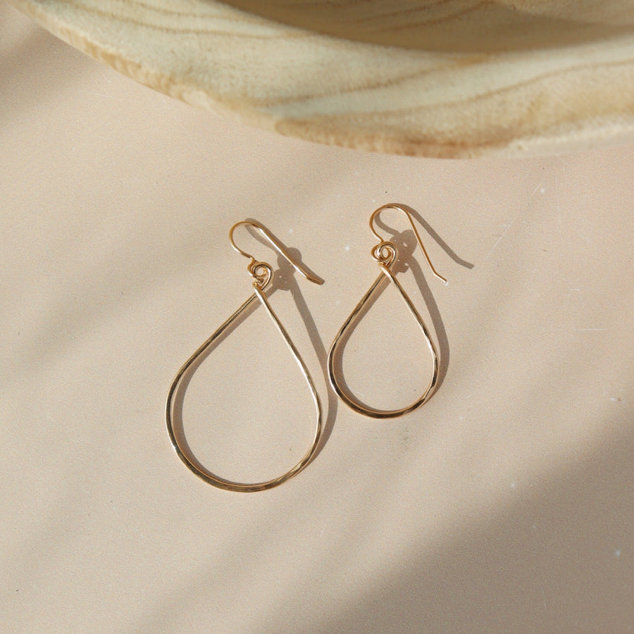 essential hoops 14k gold filled have two different earring sizes. These earrings are placed on a peach colored paper and are sitting in the sunlight. These earring come in 14k gold fill or sterling silver handmade tarnish free jewelry