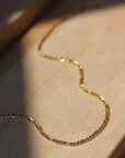 14k gold fill Gigi necklace layer on a cream colored plate. 