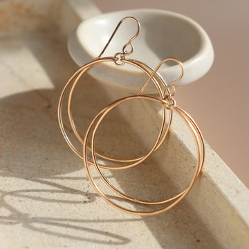 14k gold fill Parallel Hoops placed on a stone plate in the sunlight. - Token Jewelry