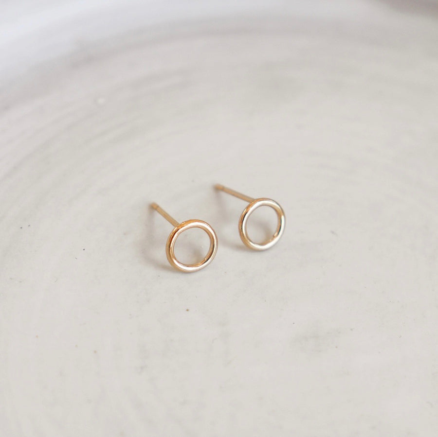 14k gold fill zero studs laid on a white plate.