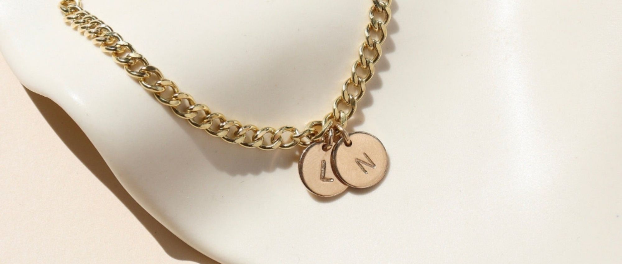 14k gold fill curb chain bracelet with personalized disc charms on a light dish