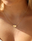 model wearing 14k gold fill half moon necklace. This necklace features a half circle hammered in the middle each side connected by the cosset chain.