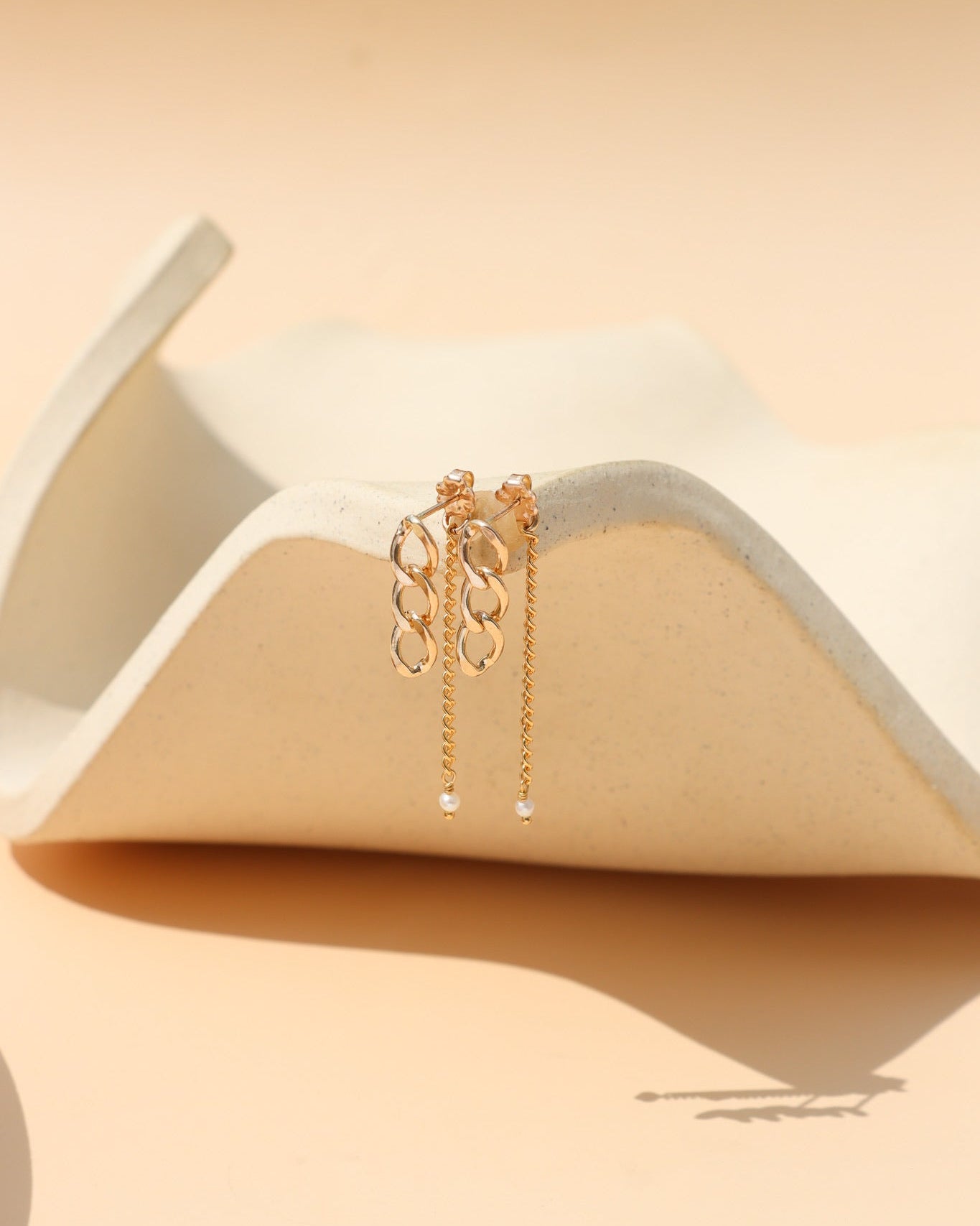 Gold stud earrings with freshwater pearls, chain link details, and a modern minimalist design, featuring the Alex Pearl Stud Earrings displayed in warm natural light.