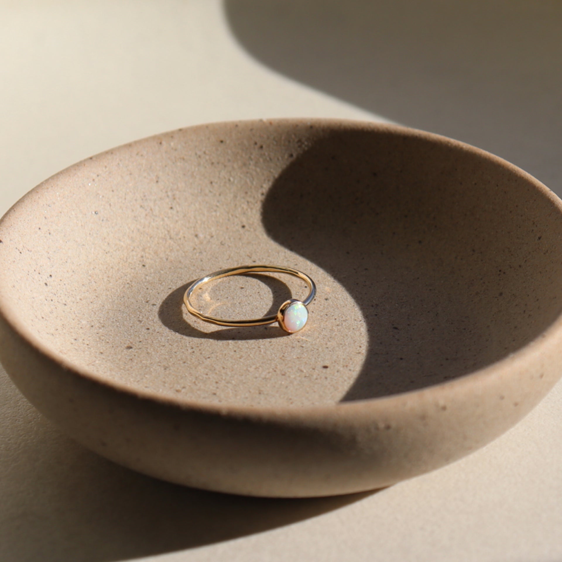 14k gold fill opal ring placed on a gray plate in the sunlight. 