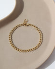 14k gold fill Demi Alexandra Bracelet laid on a tan plate in the sunlight.