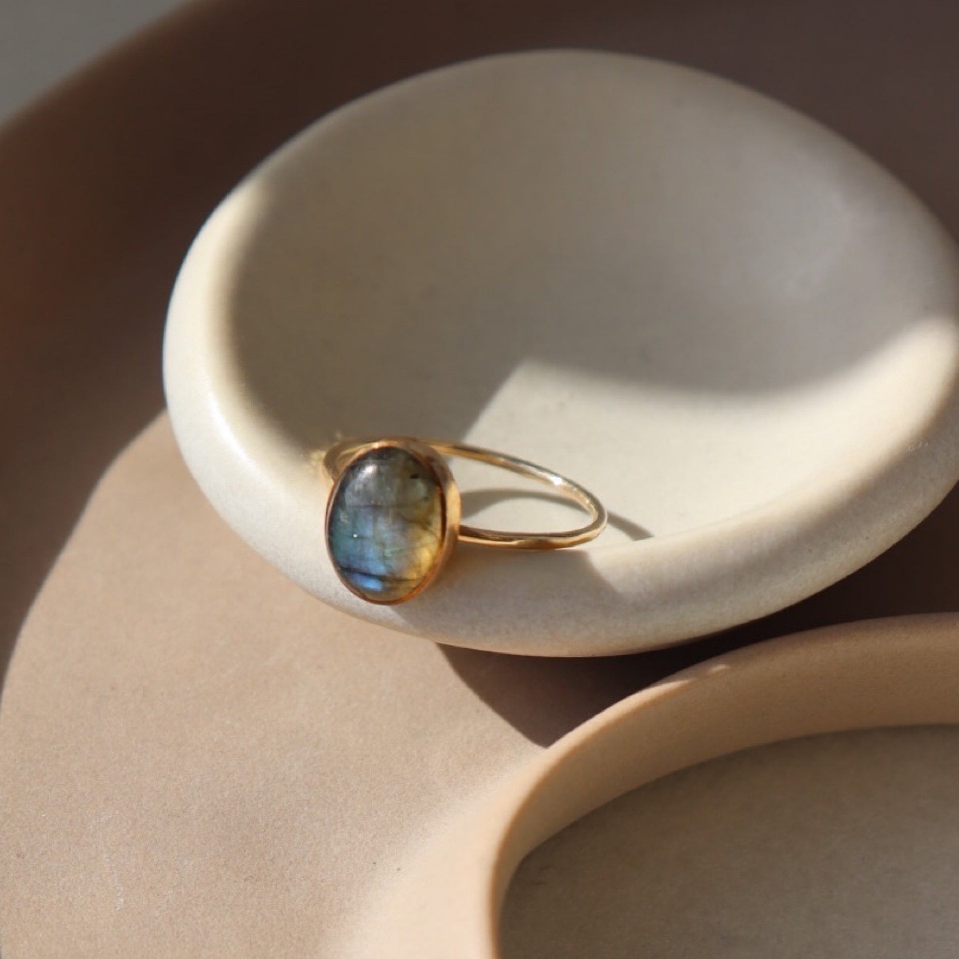 14k gold fill Labradorite Ring placed on a white dish in the sunlight. 