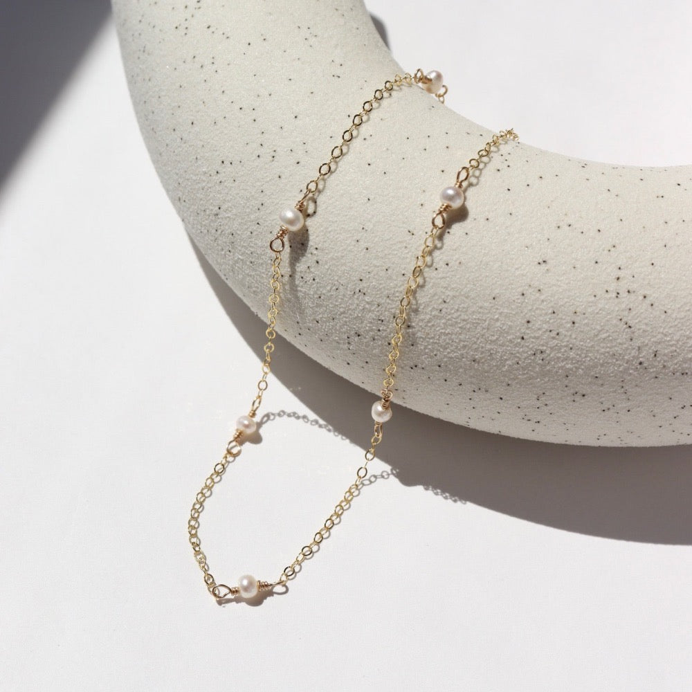 dainty pearls on a 14k gold filled chain photographed on a ceramic dish