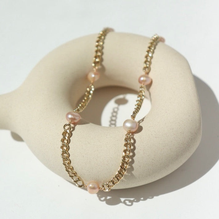 14k gold fill Rosalie anklet laid on a tan plate in the sunlight.