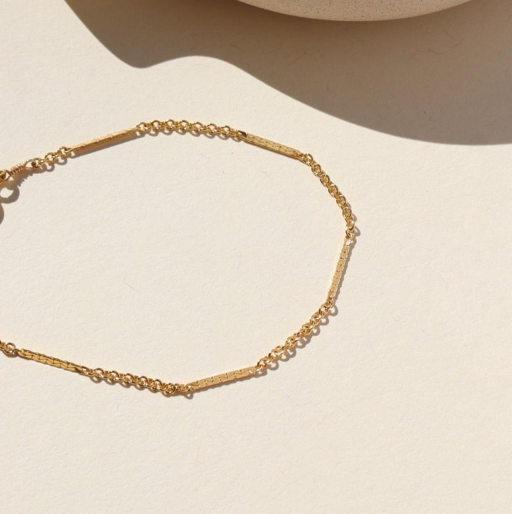 14k gold fill Sailor Bracelet laid on a tan plate in the sunlight