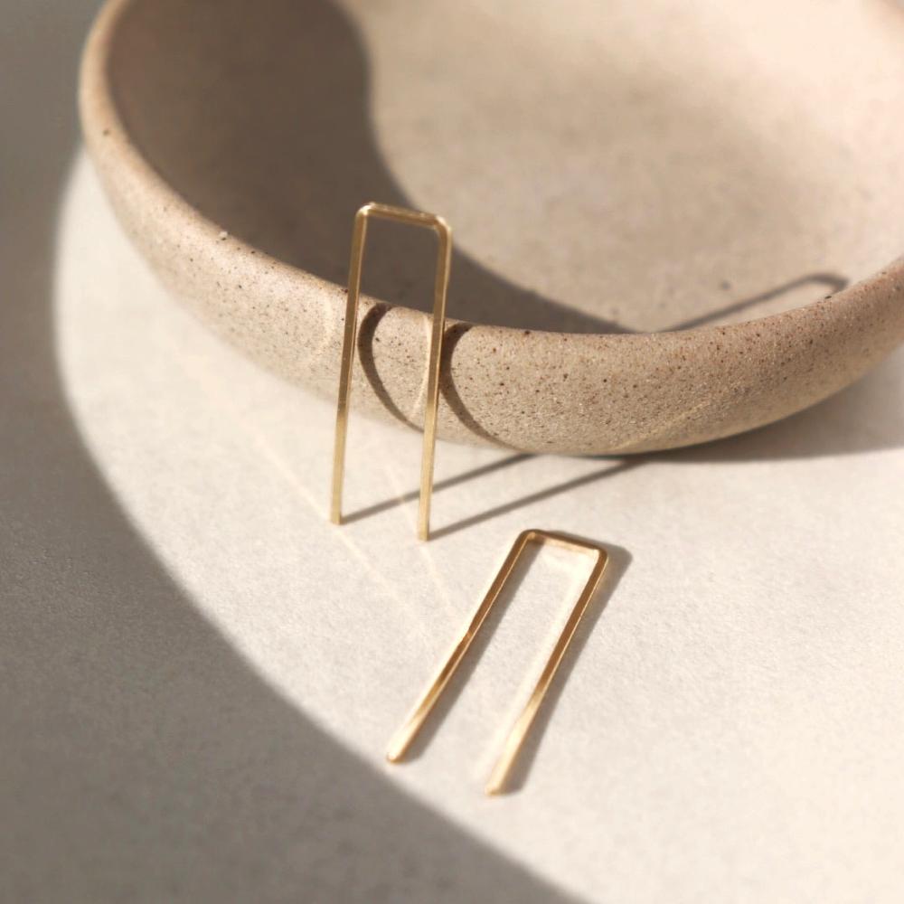 14k gold fill Staple earrings placed in the sunlight on a gray plate. A minimal earring that&#39;s perfect for everyday