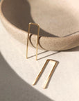 14k gold fill Staple earrings placed in the sunlight on a gray plate. A minimal earring that's perfect for everyday