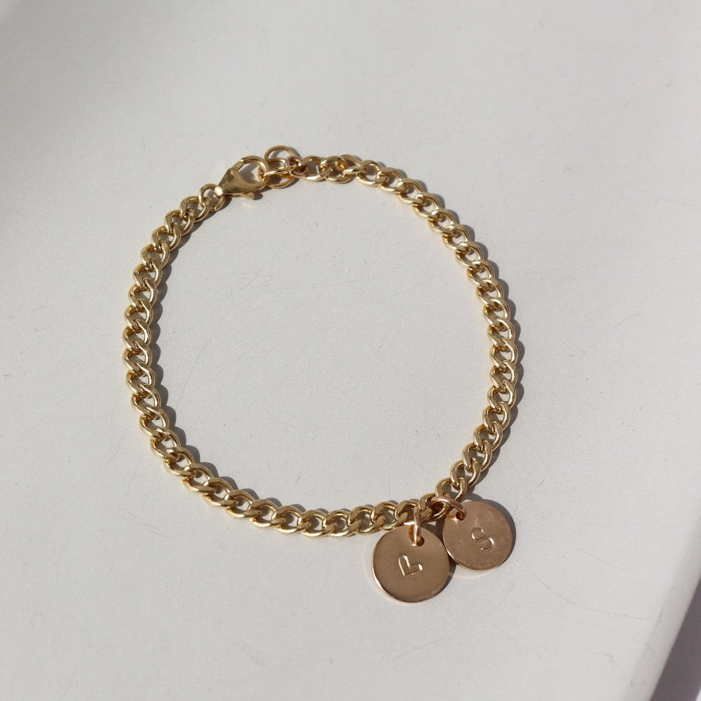 14k gold fill bold link chain Demi Alexandra Bracelet featuring two gold fill disks with a heart and an &quot;S&quot;, photographed on a white tabletop