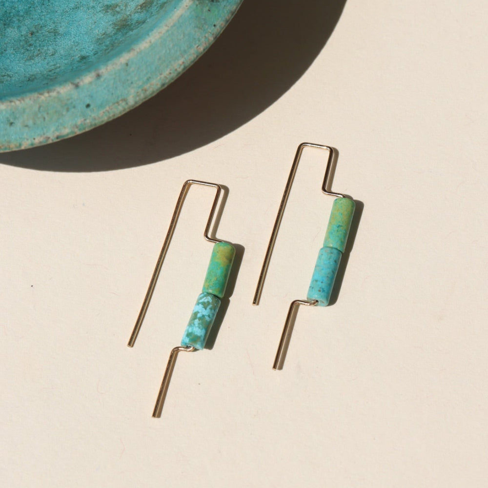 14k gold fill threaders with two turquoise tube shaped gemstones, the earrings are displayed on a cream backdrop 