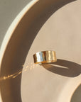 14k gold fill Luxe Ring placed on a tan plate in the sunlight. This ring features Lightly hammered and sophisticated ring cuff.