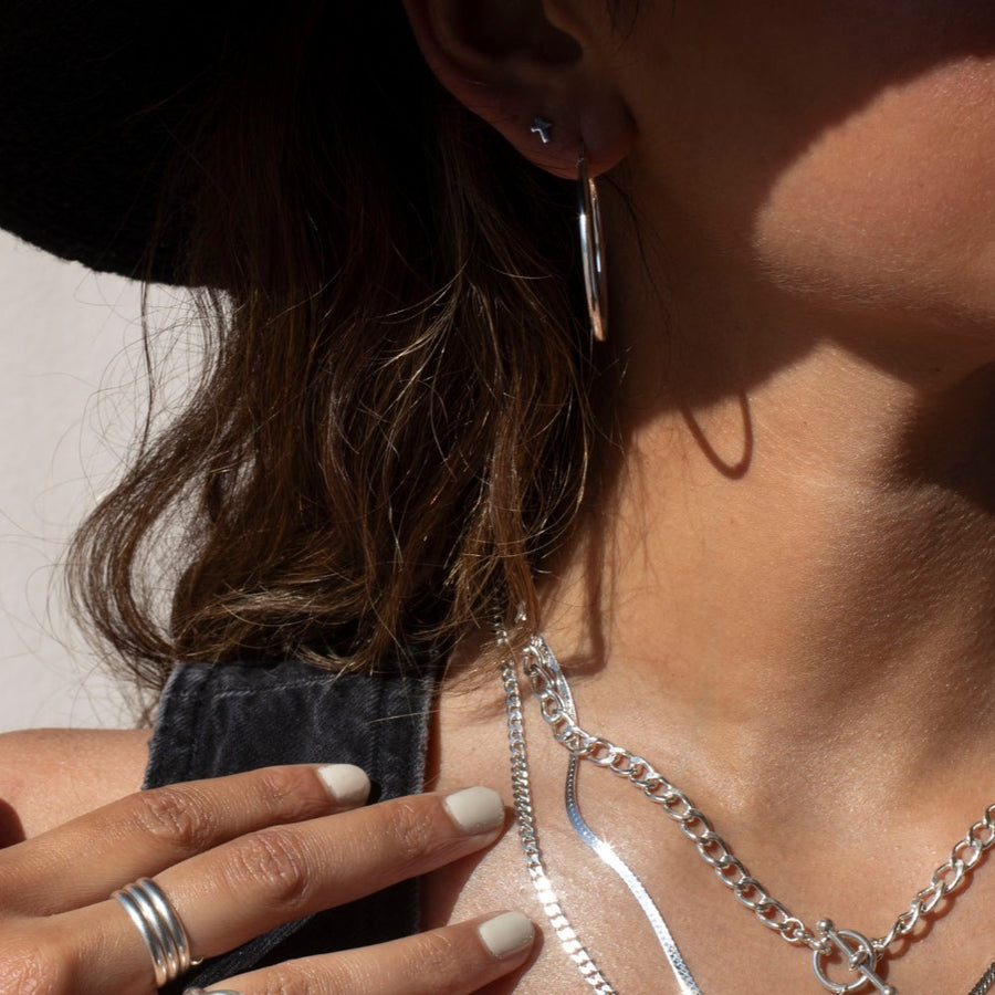 34mm classic sterling silver hoop earring photographed on a brunette model wearing a black cowboy hat and other silver jewelry made by Token Jewelry