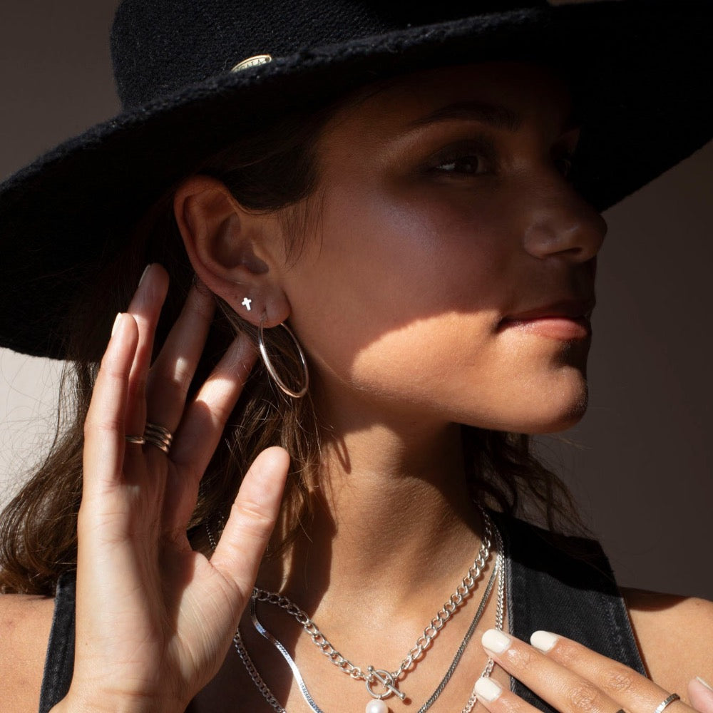 34mm classic sterling silver hoop earring photographed on a brunette model wearing a black cowboy hat and other silver jewelry made by Token Jewelry