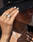 925 Sterling Silver Trinity ring spirals into three bands, photographed on a model wearing all silver jewelry and a black cowboy hat. This ring features the look of the three layered band look but its only one ring.