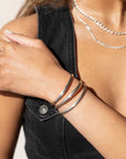 three stacked everyday cuffs from token jewelry, made with 925 sterling silver, photographed on a model wearing silver chain necklaces and a black denim vest