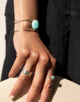 sterling silver double wire cuff bracelet featuring a large turquoise stone wired to the middle. Photographed on a model's arm wearing a black denim skirt, black cowboy boots, and silver rings