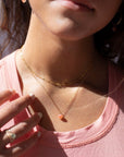 Model Wearing Cherry Blossom Necklace in 14k gold fill. This Necklace features a simple chain with a dangle gemstone. The gemstone that is featured in this necklace is the Cherry Agate Sphere. 