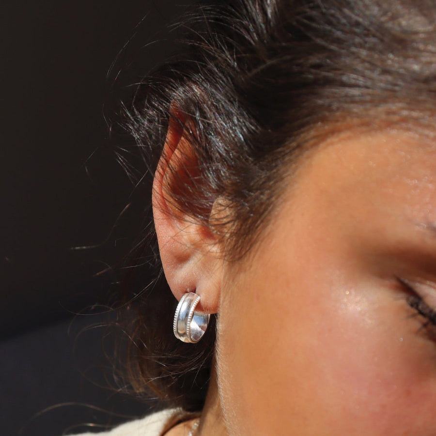 sterling silver small hoop stud earrings featuring a textured outside band, photographed on a blonde model | handmade by Token Jewelry in Eau Claire, Wisconsin