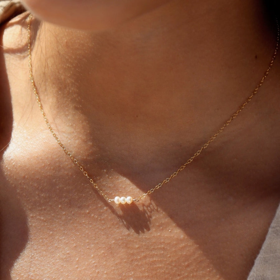 three freshwater pearls lined up on a 14k gold fill simple chain, made by Token Jewelry, photographed on a model