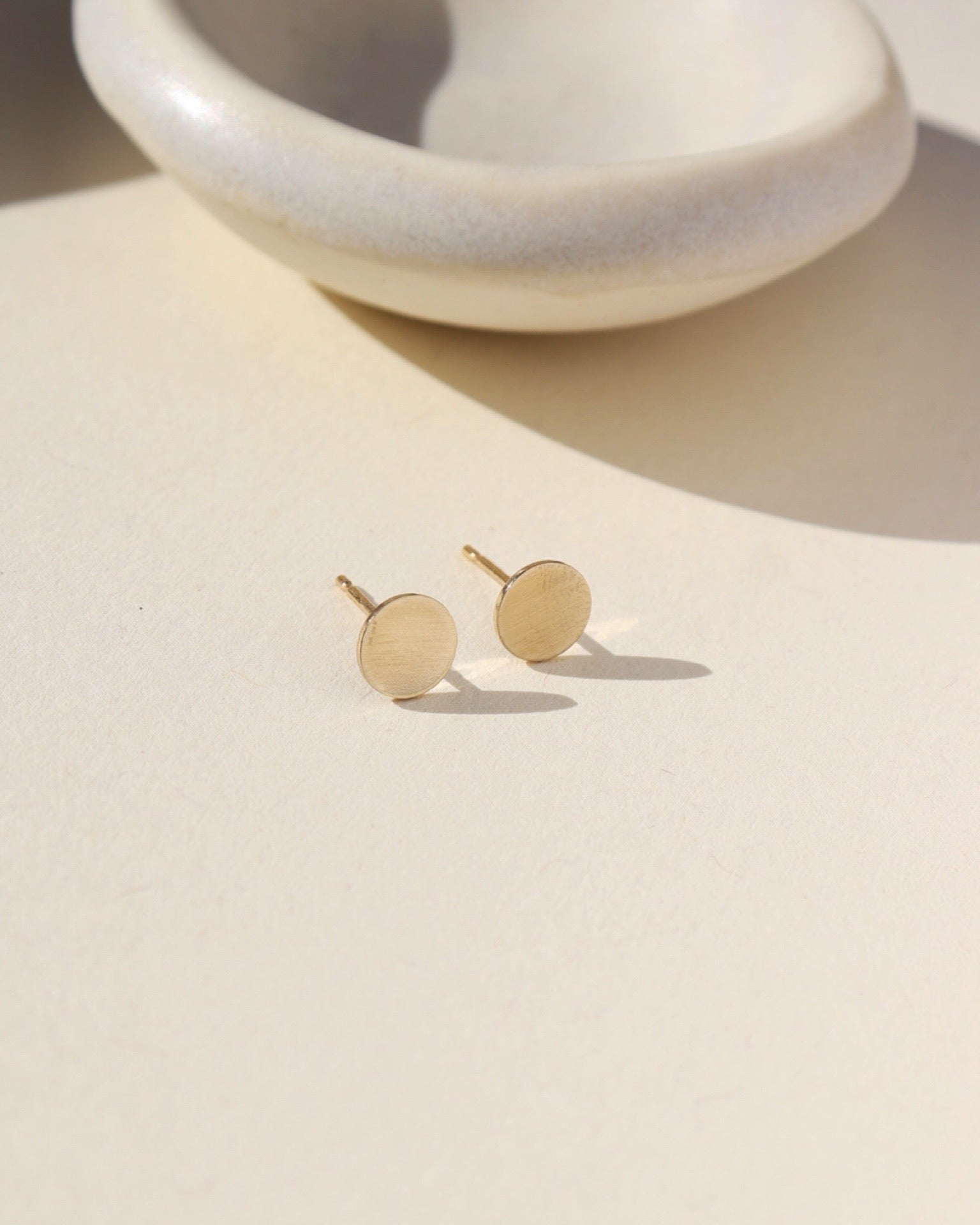 14k gold fill circle studs near small dish 