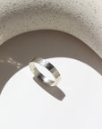 925 sterling silver cigar style ring laid on a white plate in the sunlight. This ring features a hammered band