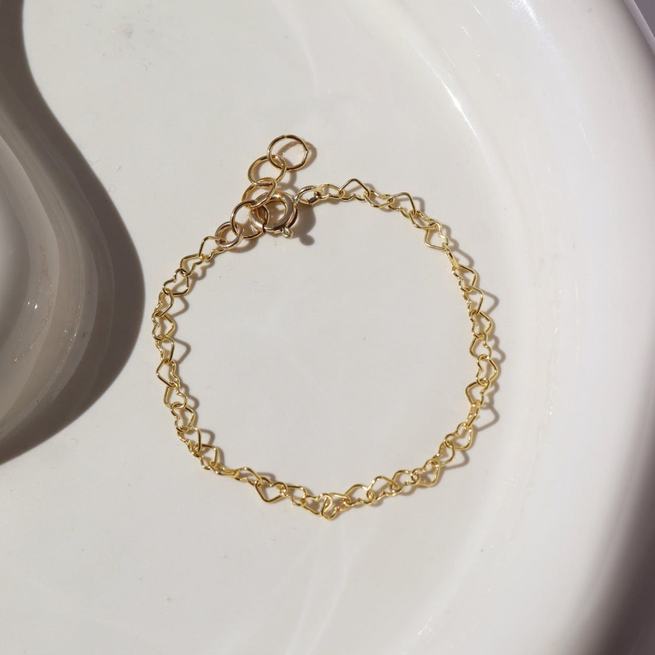 14k gold fill heart link chain in children&#39;s sizes, photographed on a ceramic white plate