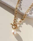 14k gold fill chain with a toggle clasp and large pearl, photographed on a sunlit tabletop