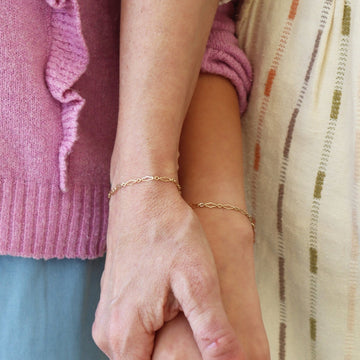 Mother and daughter hold hands while wearing matching 14k gold fill Clara Chain bracelets by Token Jewelry
